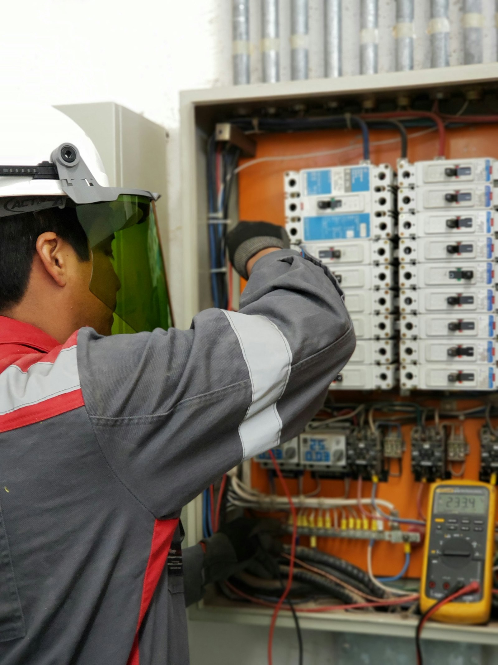 Profissional utilizando EPIs durante teste em painel elétrico