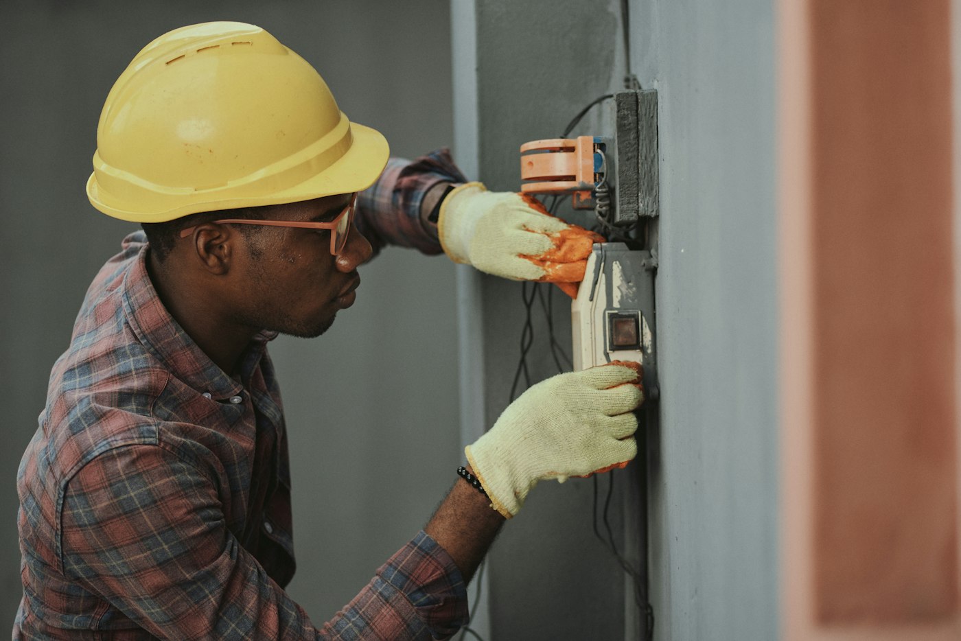 Eletricista com capacete de segurança realizando instalação elétrica